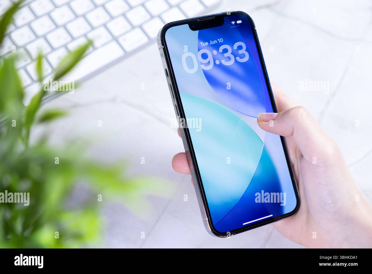 Poznan, Polonia - 10 giugno 2025: Primo piano di una mano che tiene in mano il nuovo iPhone Apple, con la sua ultima schermata di blocco iOS 26 e il design Liquid Glass Foto Stock