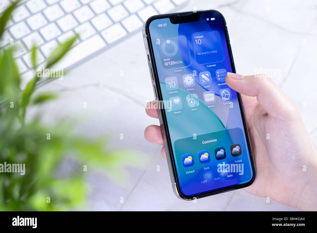 Poznan, Polonia - 10 giugno 2025: Primo piano della mano di una persona utilizzando un telefono cellulare con un'interfaccia concettuale iOS 26 Liquid Glass per un personale avanzato Foto Stock