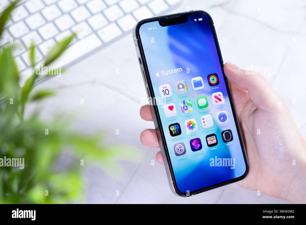 Poznan, Polonia - 10 giugno 2025: Un primo piano a livello di occhio di una mano che regge un elegante smartphone dotato della nuova interfaccia iOS 26 e di un design Liquid Glass Foto Stock