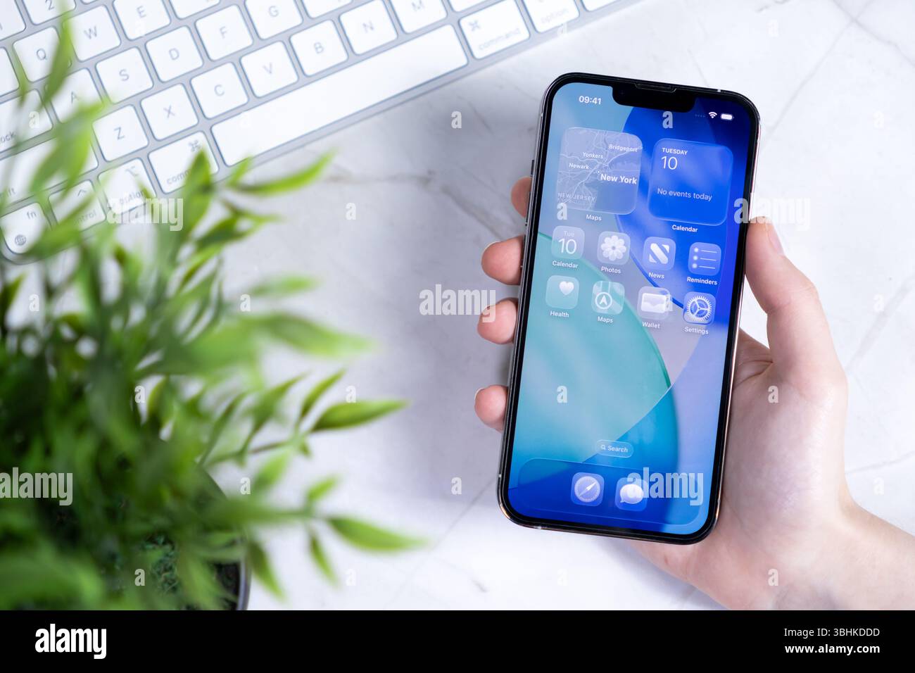 Poznan, Polonia - 10 giugno 2025: Una mano regge uno smartphone moderno che mostra il nuovo sistema operativo IOS 26 con design Liquid Glass per la console digitale Foto Stock