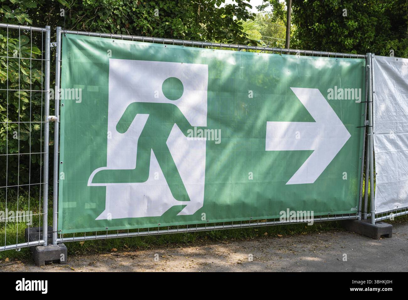 Bauzaun, Absperrung, barre mit einem Piktogramm einer fluechtenden person, Symbos fuer Notausgang, Fluchtweg, Sicherheit bei Veranstaltungen wie Op Foto Stock
