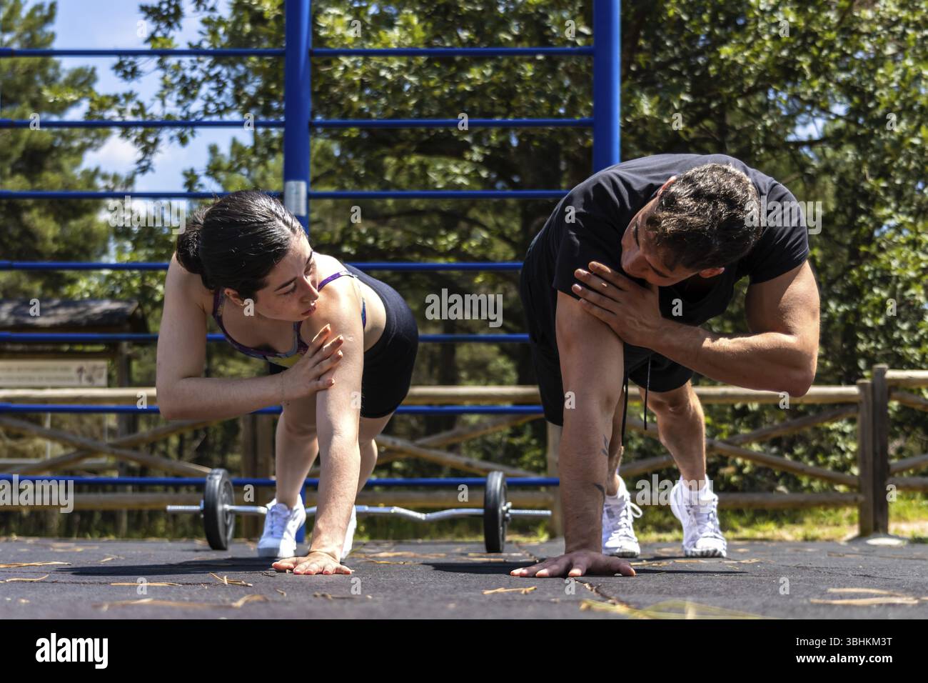 Un'atleta esegue push-up come osserva da vicino il suo allenatore, garantendo una forma corretta durante un'intensa sessione di allenamento all'aperto Foto Stock
