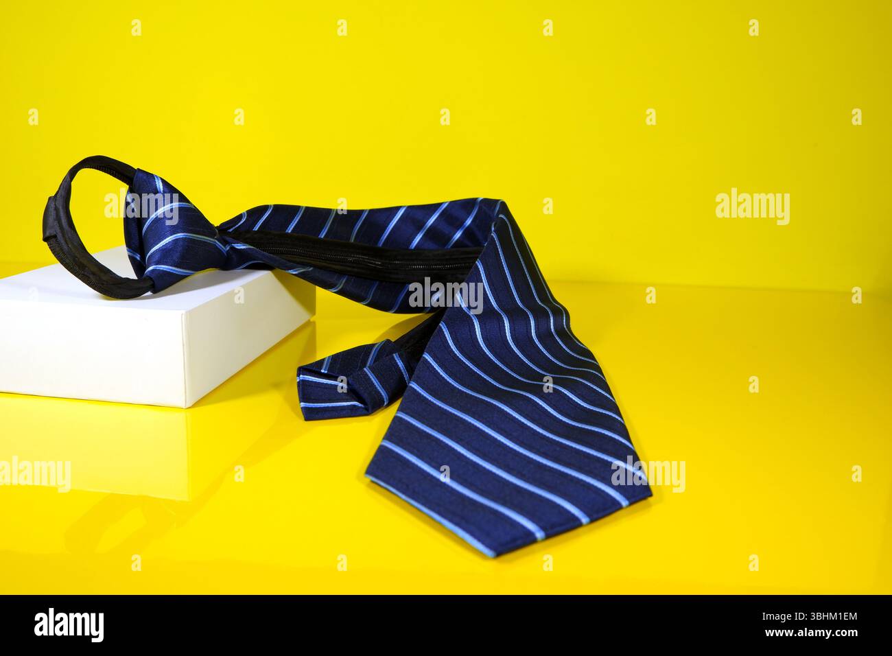 Una cravatta con zip isolata su sfondo giallo Foto Stock