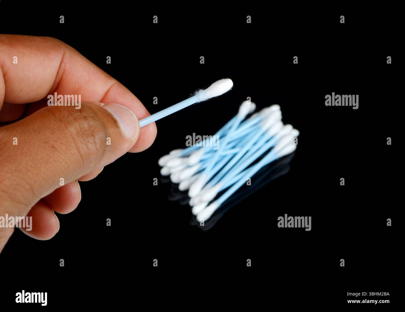 Batuffolo di cotone per la pulizia delle cere che si tiene per mano su sfondo nero Foto Stock