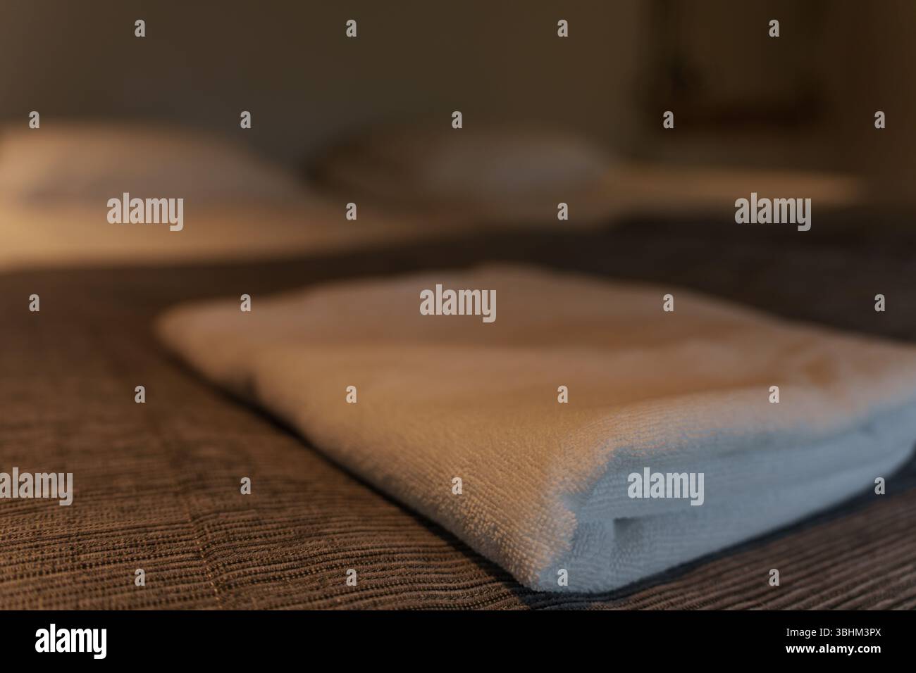 Primo piano di un asciugamano piegato sul letto di un hotel. Foto Stock