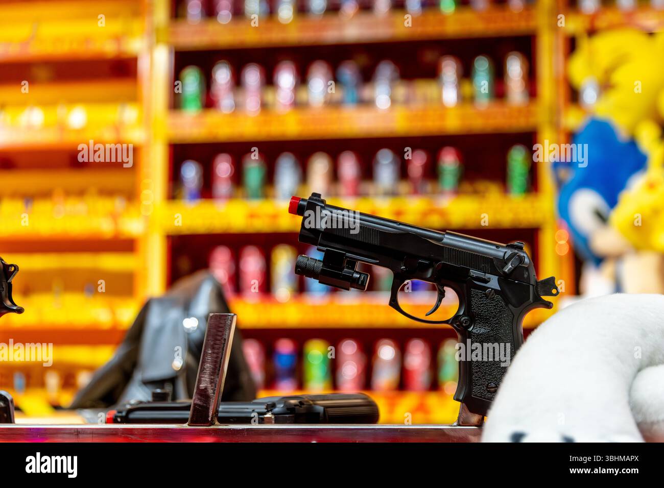 Angera, Lombardei - Italia - 07-02-2024: Primo piano di una galleria di tiro con pistole giocattolo e colorate lattine di sfondo in un carnevale di Angera, Ital Foto Stock