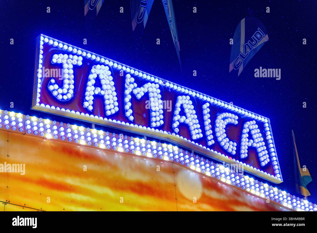 Angera, Lombardei - Italia - 07-02-2024: Un grande cartello giamaicano illuminato di notte in occasione di un carnevale, circondato da luci e bandiere accese ad Angera, Ital Foto Stock