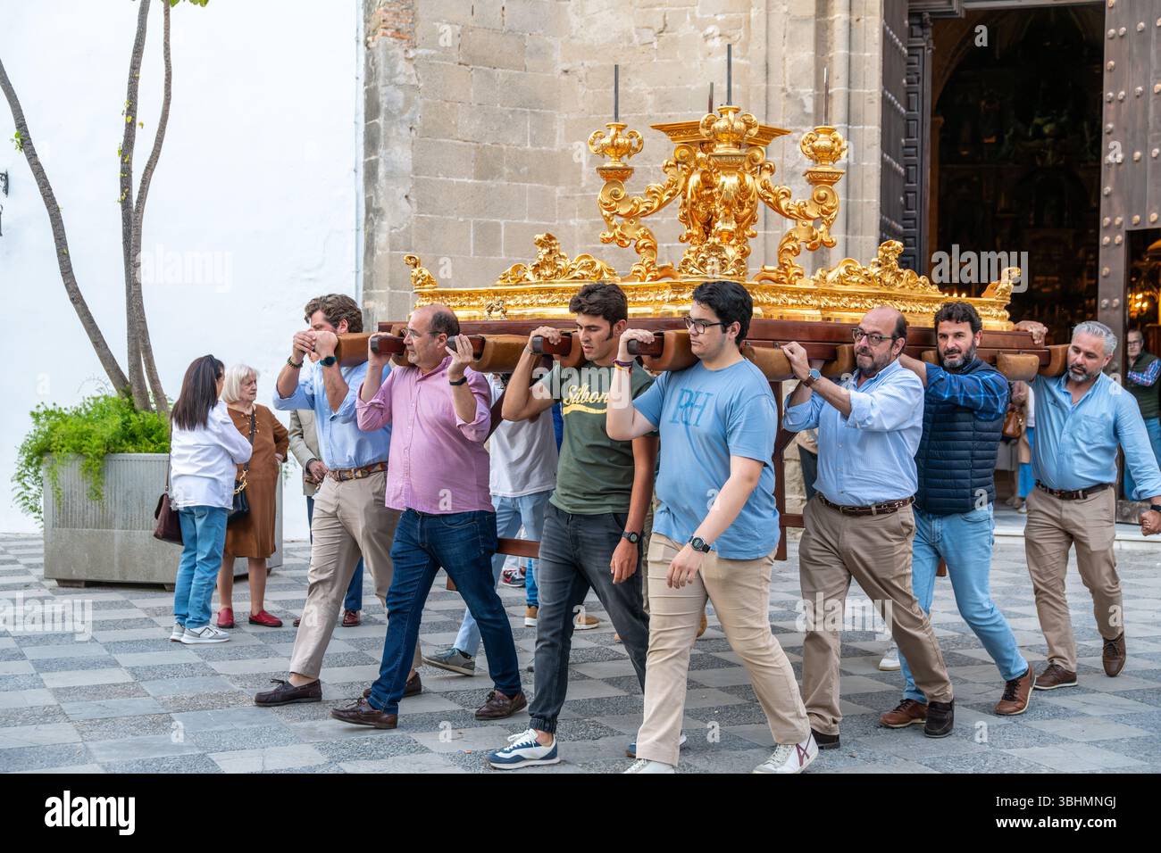Jerez de la Frontera, Cadice - Spagna - 04-23-2024: Le persone portano una piattaforma di processione dorata adornata da intricate decorazioni e portacandele duri Foto Stock