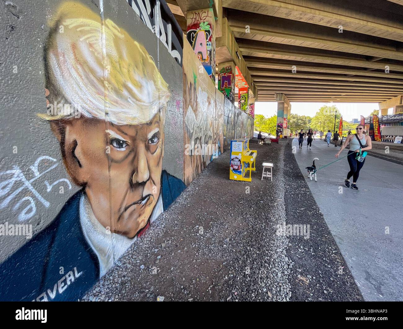 Atlanta, GA / USA - 23 settembre 2023: La gente passa l'arte dei graffiti del mugshot di Trump dipinto su un muro lungo l'area ricreativa di Atlanta Beltline. Foto Stock