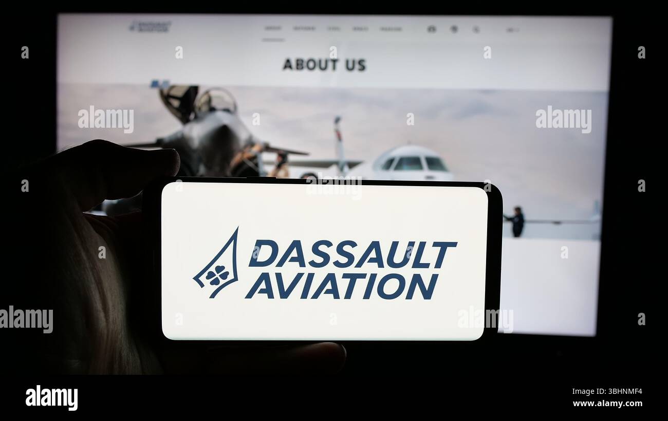 Stoccarda, Germania - 03-13-2025: Persona che detiene il cellulare con il logo della società francese Dassault Aviation S.A. sullo schermo davanti alla pagina web. Foto Stock