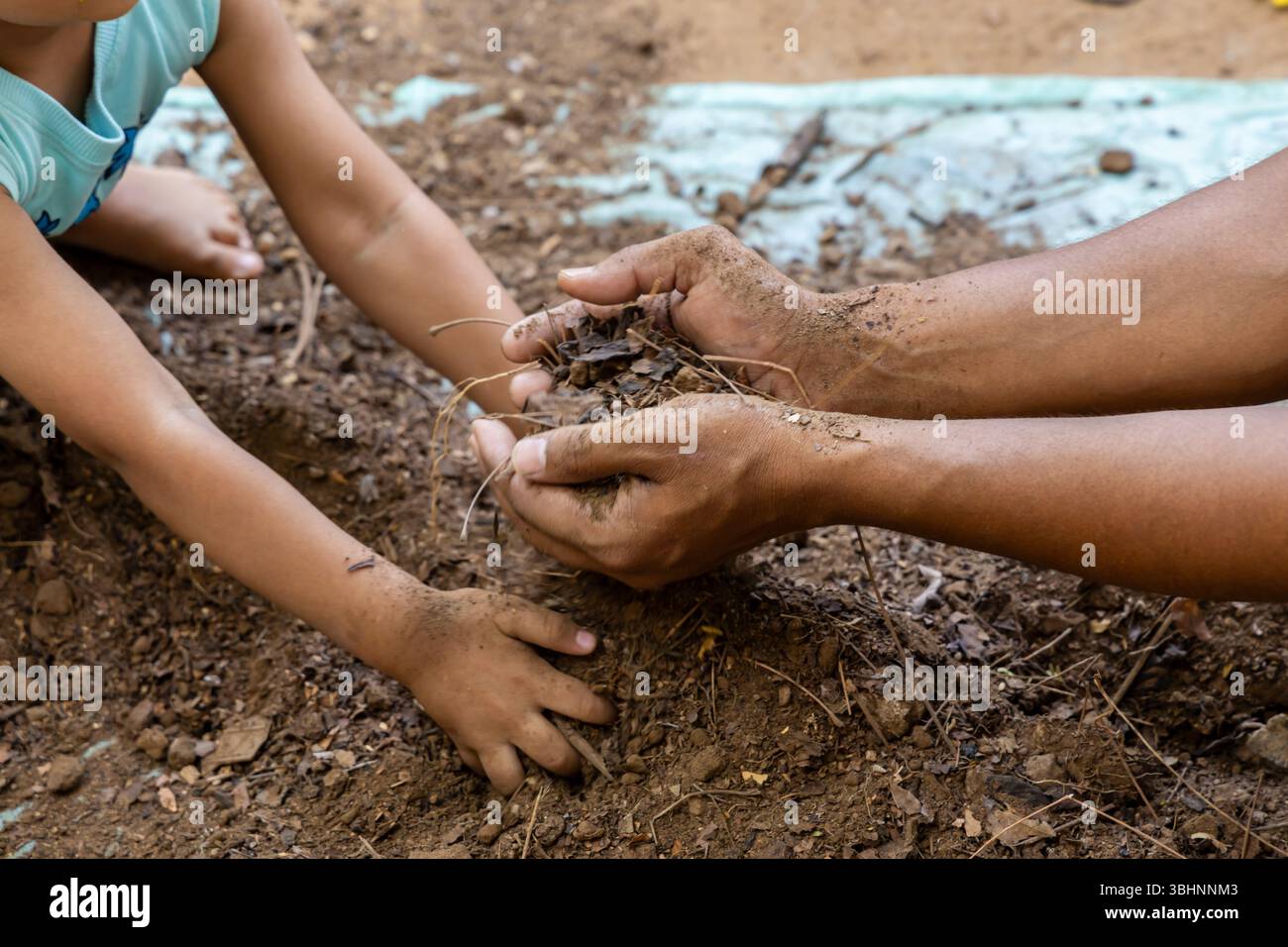 incollaggio di adulti e bambini durante la preparazione di terreni da giardino puliti con tema "salva terra" all'aperto Foto Stock