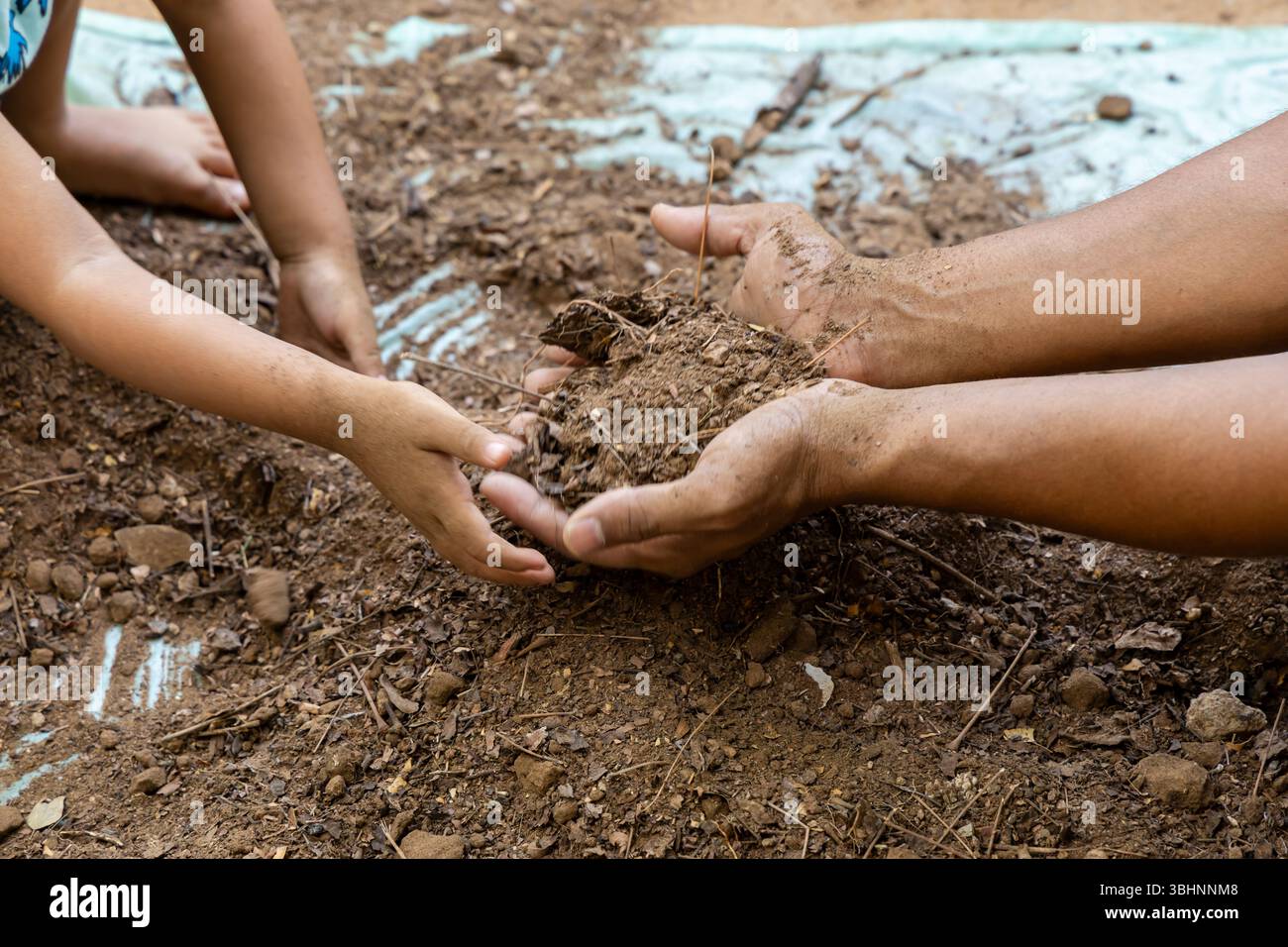 incollaggio di adulti e bambini durante la preparazione di terreni da giardino puliti con tema "salva terra" all'aperto Foto Stock