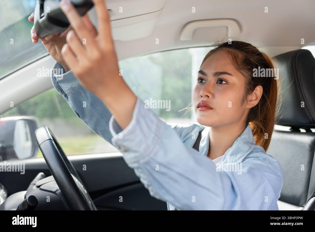 donna regola lo specchietto retrovisore dell'auto prima della guida, guida con intento, guida sicura, pratica di guida, donna allegra seduto comodamente sul sedile del conducente wi Foto Stock