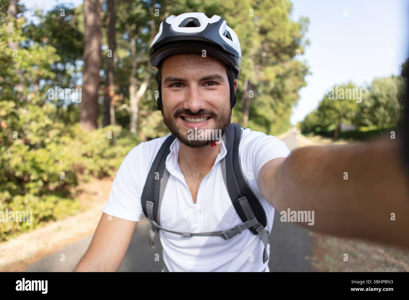 uomo allegro con casco in bicicletta che scatta foto selfie Foto Stock