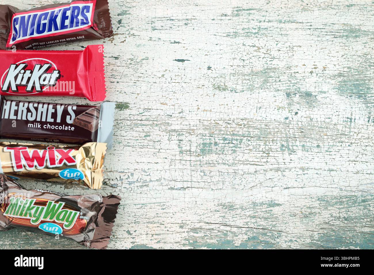 Tavolette di cioccolato, pacchetti misti su un vecchio sfondo di legno: Kit Kat, Snickers, via Lattea, Twix e Hershey's, concetto di cibo e spuntini Foto Stock