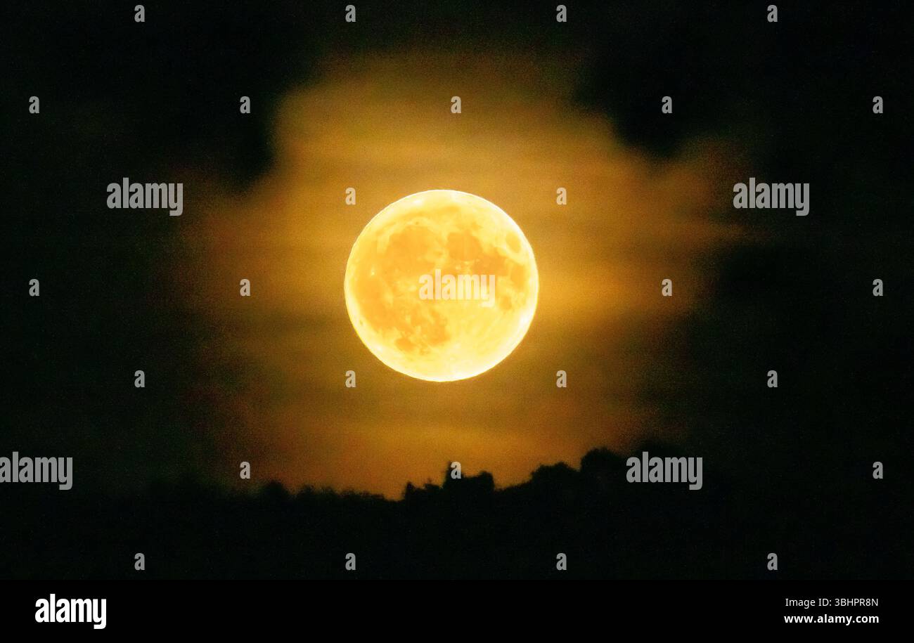 Cumbria, Regno Unito. 11 giugno 2025. La luna di fragole sulla Cumbria. Gli astronomi nell'emisfero settentrionale avvistarono una luna quasi piena seduta molto bassa nel cielo meridionale, facendola apparire molto più grande del solito. Crediti: John Eveson/Alamy Live News Foto Stock