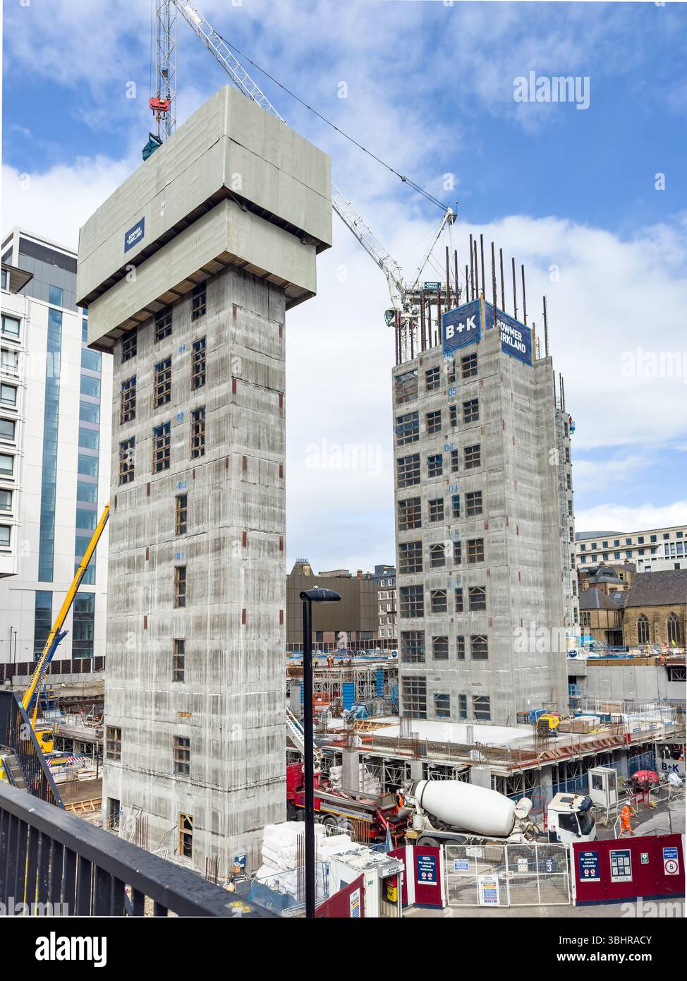 Cantiere con due alti edifici in fase di sviluppo circondati da gru e skyline di newcastle con nuclei di sollevamento in cemento - Immagine stock catturata con smartphone