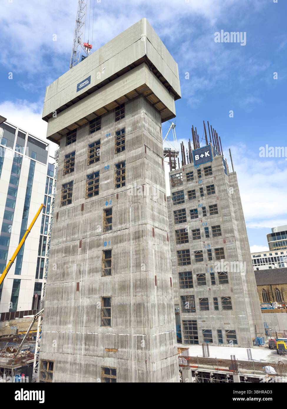 Cantiere con due alti edifici in fase di sviluppo circondati da gru e skyline di newcastle con nuclei di sollevamento in cemento - Immagine stock catturata con smartphone