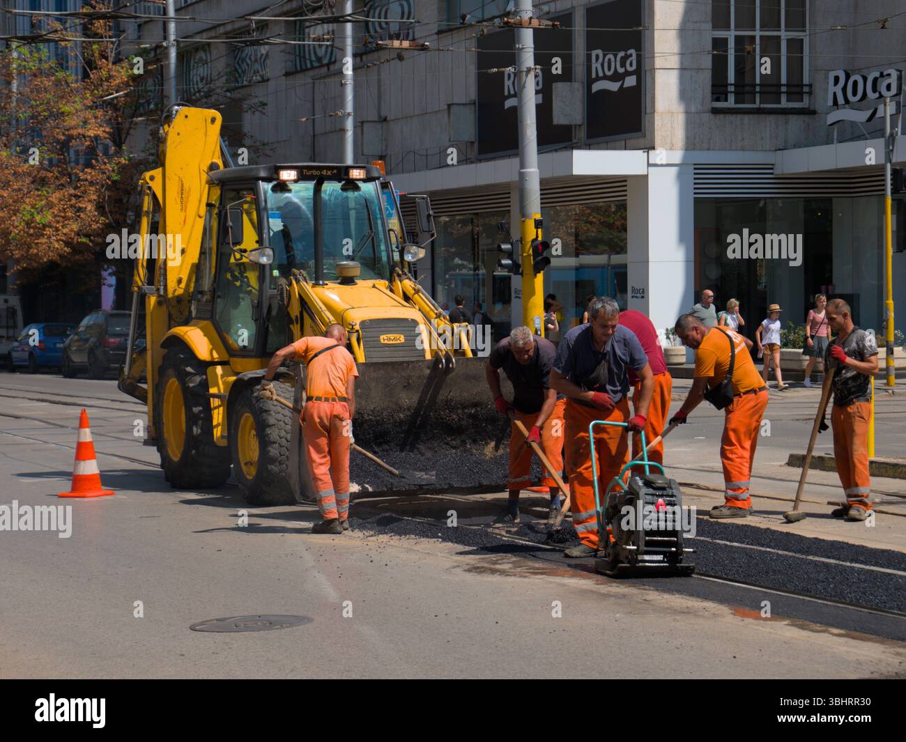 Personale addetto alla manutenzione stradale che lavora con macchinari e utensili pesanti per le riparazioni dell'asfalto a Sofia, Bulgaria Foto Stock