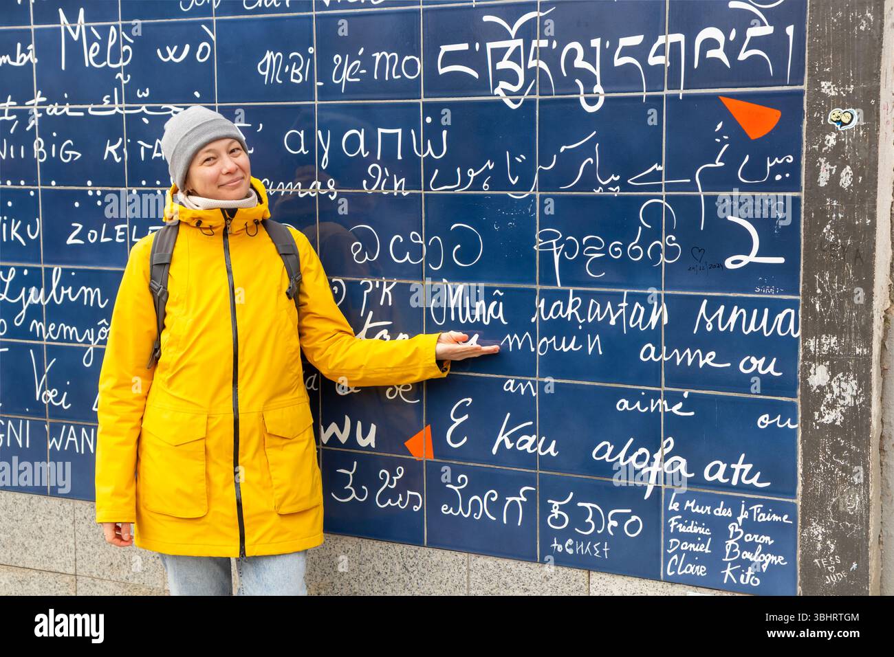 Parigi, Francia - 28 febbraio 2025: Una turista finlandese sorridente di fronte al muro dell'amore (le Mur des Je taime) a Montmartre, Parigi. La vibra Foto Stock
