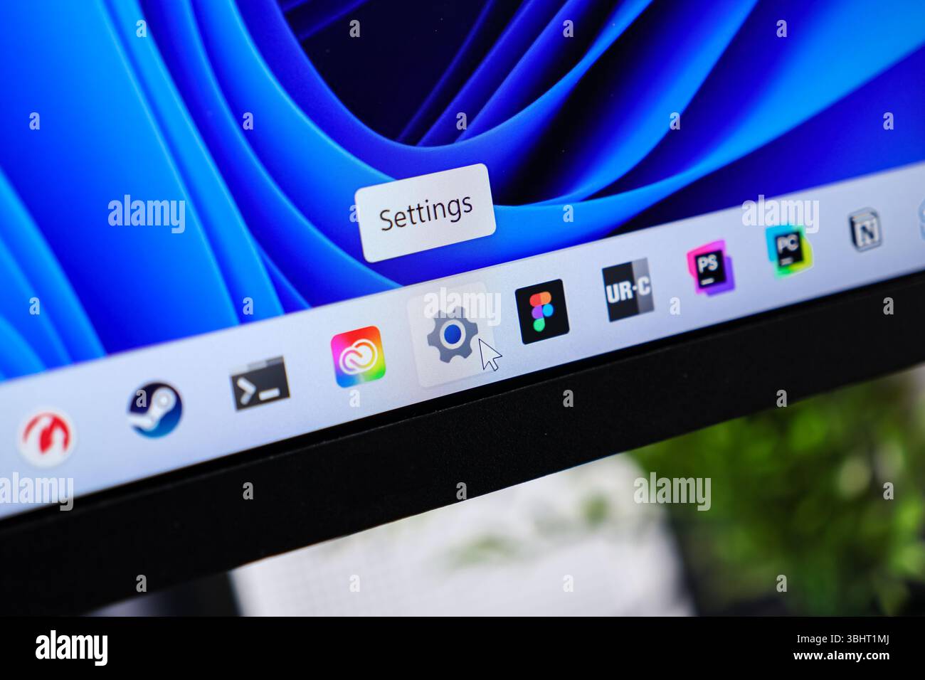 Poznan, Polonia - 6 giugno 2025: Schermata che mostra l'icona "Impostazioni" sulla barra delle applicazioni, con un cursore del mouse che indica la configurazione del sistema e la personalizzazione Foto Stock
