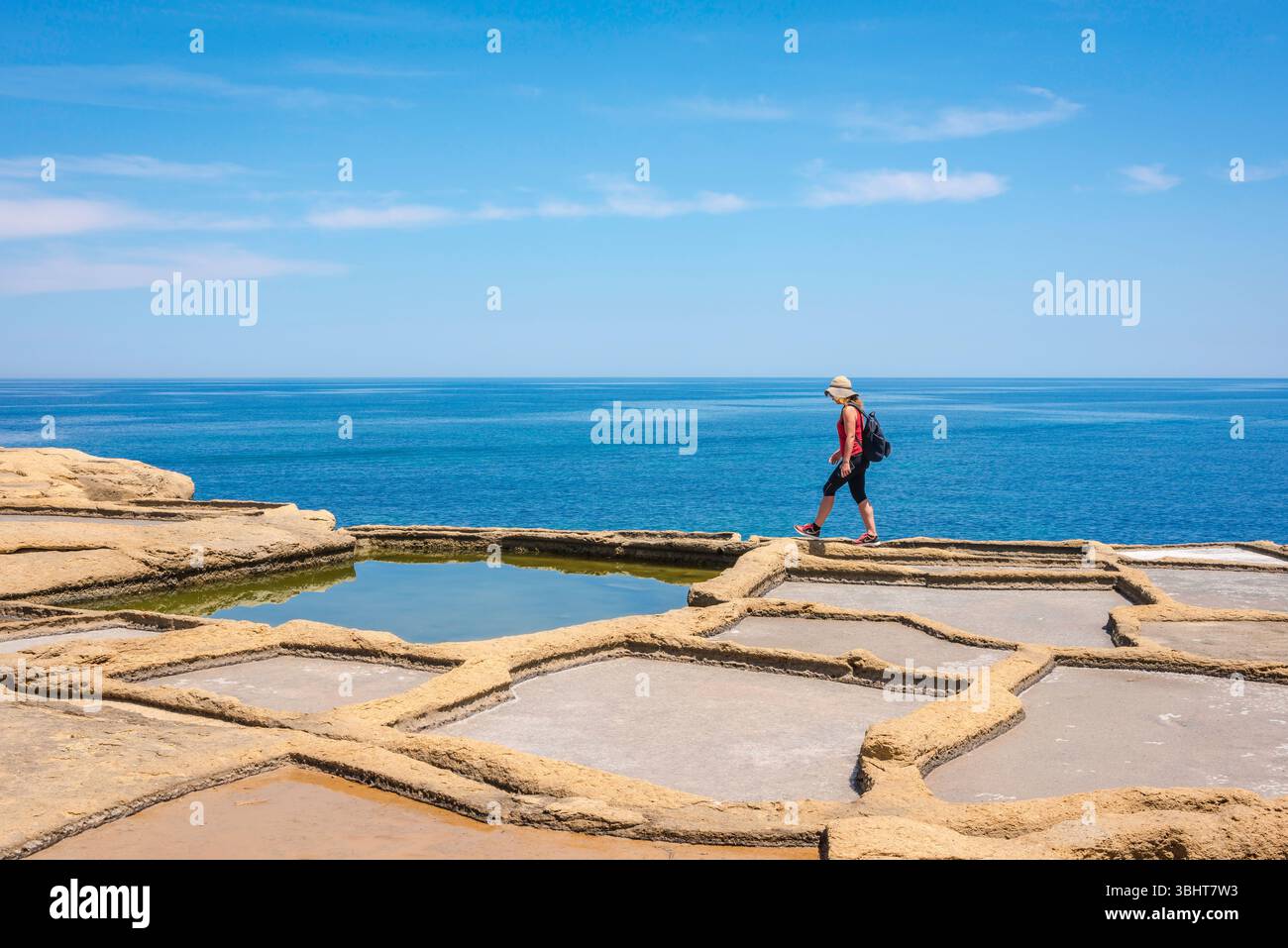 Saline di Malta, vista di una giovane donna viaggiatrice che esplora le antiche saline situate nella baia di Xwejni sulla costa settentrionale di Gozo, Malta. Foto Stock