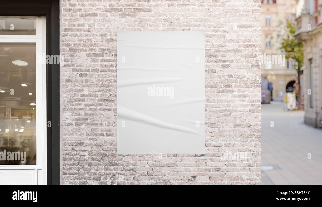 Poster bianco sulla parete in mattoni vicino alla vetrina del negozio e all'angolo della strada urbana, perfetto per branding, pubblicità e presentazioni di mockup di design di poster Foto Stock