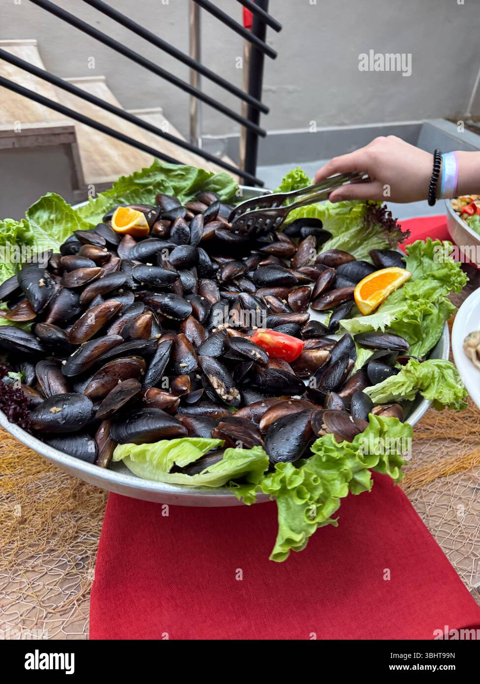 Donna che serve cozze in scatola sul suo piatto. Femmina che prende a mano frutti di mare conservati. Foto Stock