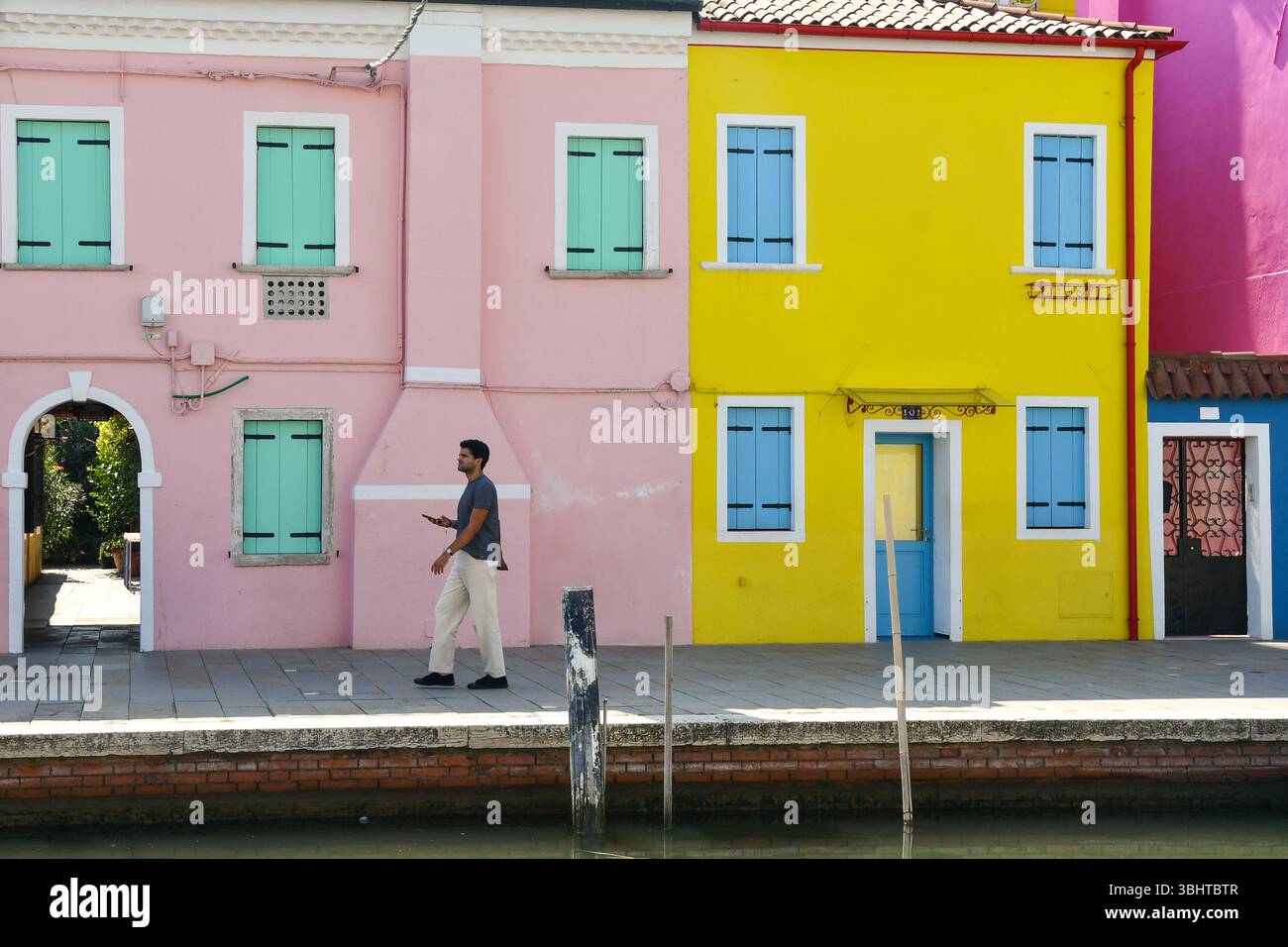 Una passeggiata turistica sul lungomare di via Giudecca, sulla famosa e colorata isola di Burano, nella laguna veneta, Venezia, Veneto, Italia Foto Stock