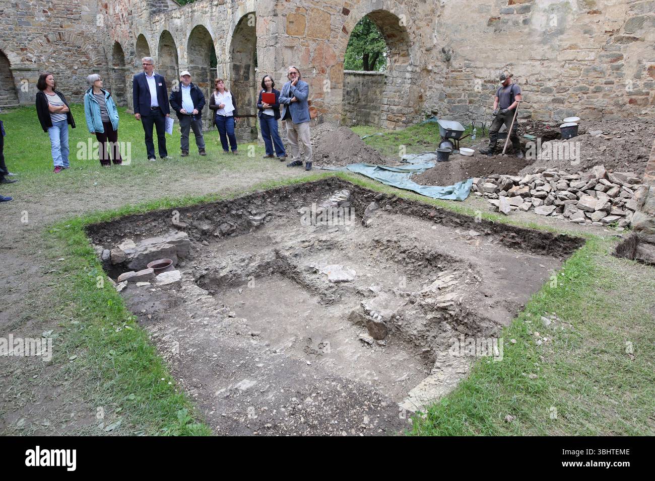 11 giugno 2025, Sassonia-Anhalt, Oebisfelde-Weferlingen: I partecipanti a una conferenza stampa dell'Ufficio di Stato Sassonia-Anhalt per la conservazione dei monumenti e dell'archeologia si trovano presso il sito di scavo nelle rovine della chiesa collegiata di Santa Maria a Walbeck. L'Ufficio di Stato Sassonia-Anhalt per la conservazione dei monumenti e dell'archeologia ha presentato i reperti attuali degli scavi di ricerca presso le rovine della chiesa collegiata di Santa Maria. Nel 1932, fu trovata una presunta tumba medievale (tomba indipendente sotto forma di sarcofago) fatta di stucco, che ora si trova nella chiesa del villaggio di Walbeck Foto Stock