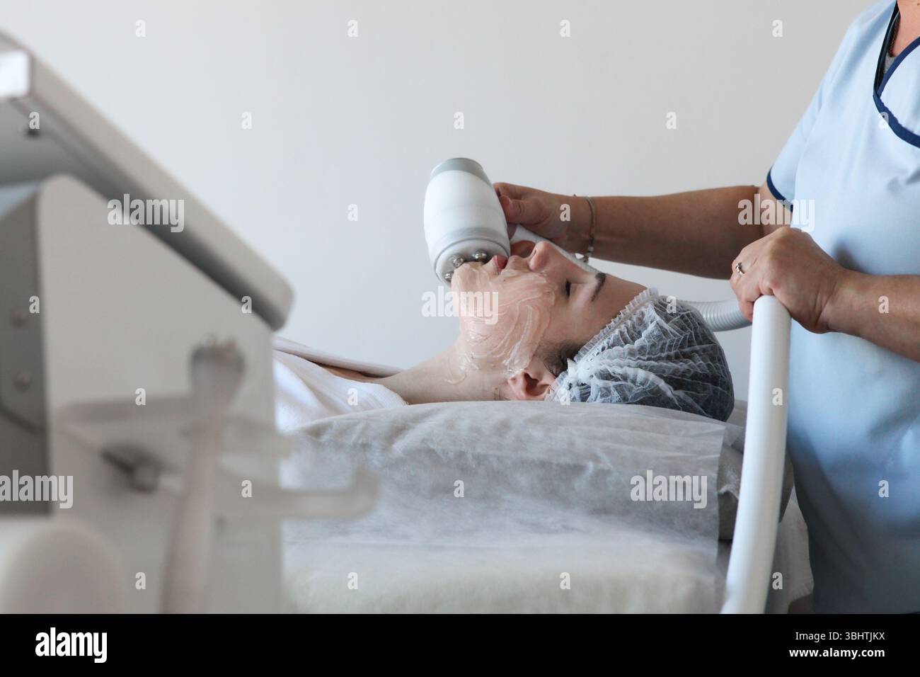 Giovane donna che riceve una crioterapia trattamento facciale a radiofrequenza presso una clinica di bellezza effettuata da specialisti con attrezzature specializzate, Foto Stock