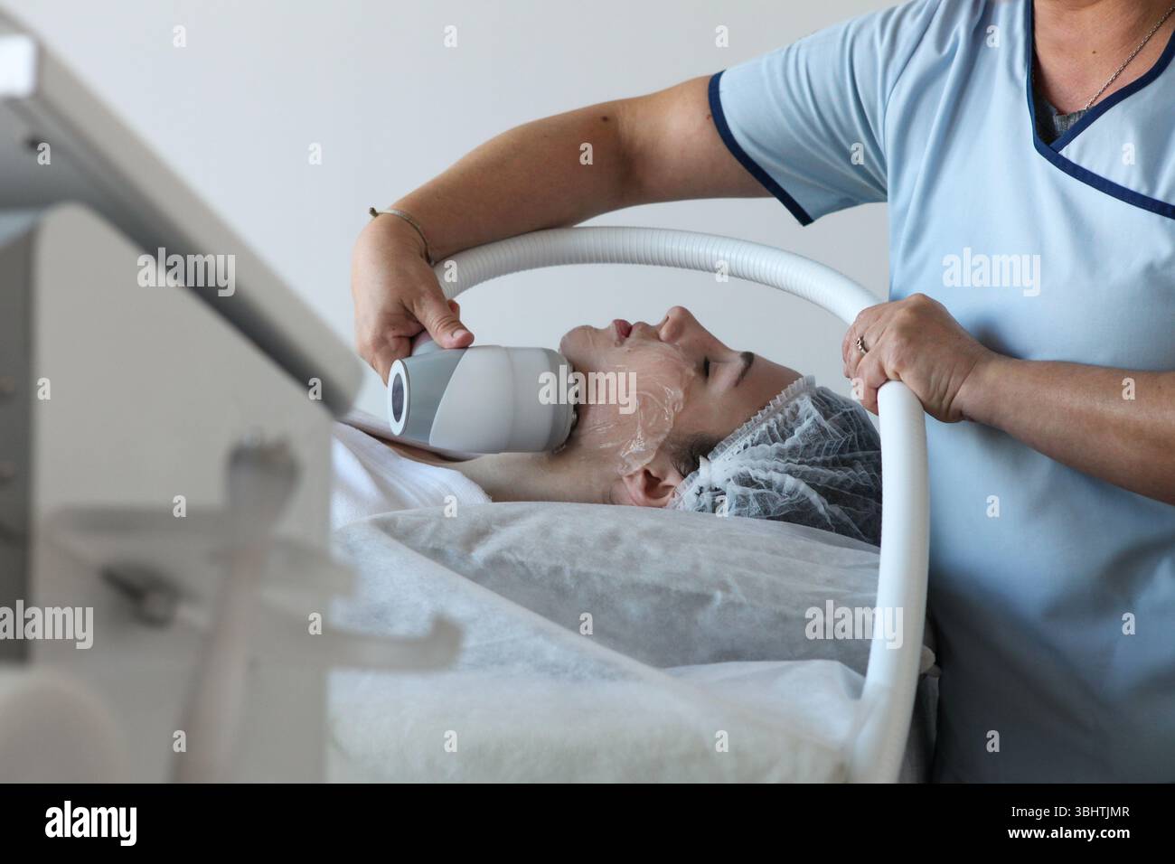 Giovane donna che riceve una crioterapia trattamento facciale a radiofrequenza presso una clinica di bellezza effettuata da specialisti con attrezzature specializzate, Foto Stock