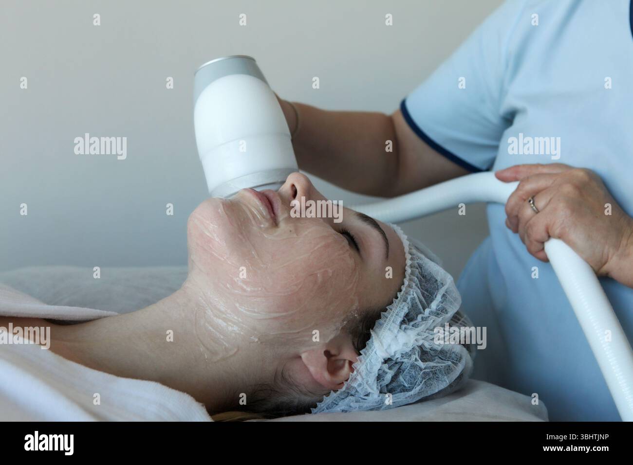 Giovane donna che riceve una crioterapia trattamento facciale a radiofrequenza presso una clinica di bellezza effettuata da specialisti con attrezzature specializzate, Foto Stock