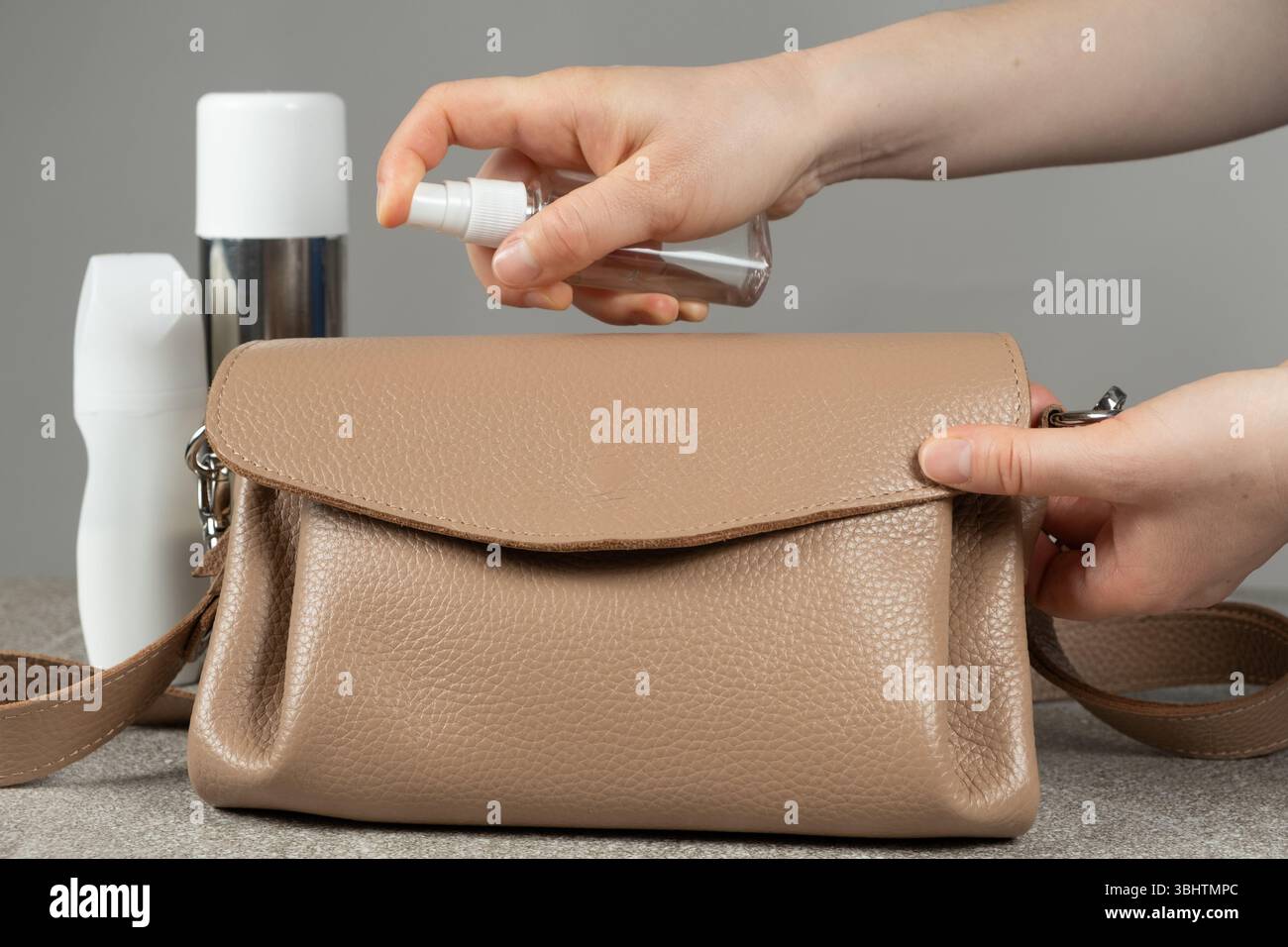 Cura dei prodotti in pelle. Applicazione di uno spray speciale del prodotto sulla superficie di una borsa in pelle Foto Stock