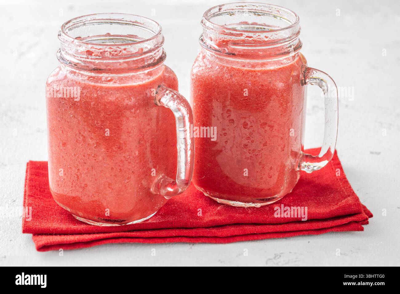 Frullato tropicale cremoso con ciliegia, banana e ananas nei vasetti mason Foto Stock