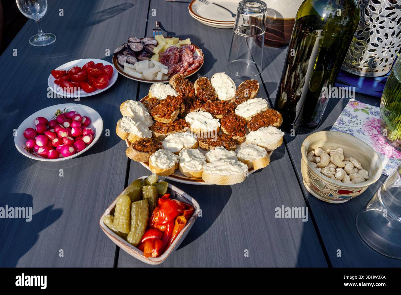 Tavolo con piatti pieni di cibo per feste, spuntini o cene. Verdure, pasta a fette con spalmabile, anacardi e vino. Foto Stock