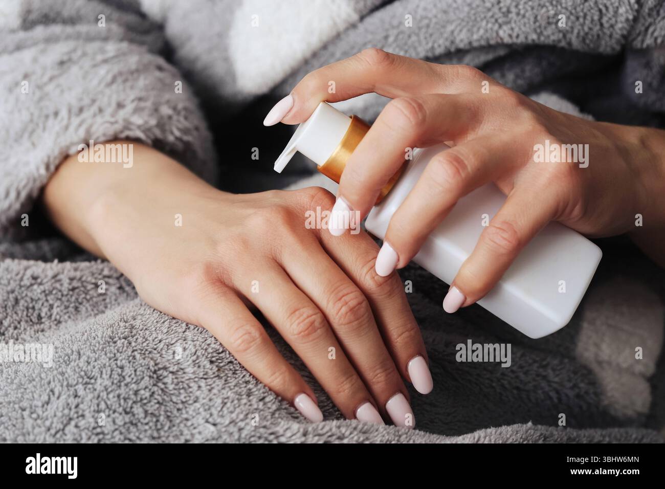 Applicare la panna a mano. Concetto di routine per la cura della pelle. Idratante per la cura delle mani. Primo piano con accappatoio. Relax e benessere. Pelle morbida e naturale. Foto Stock