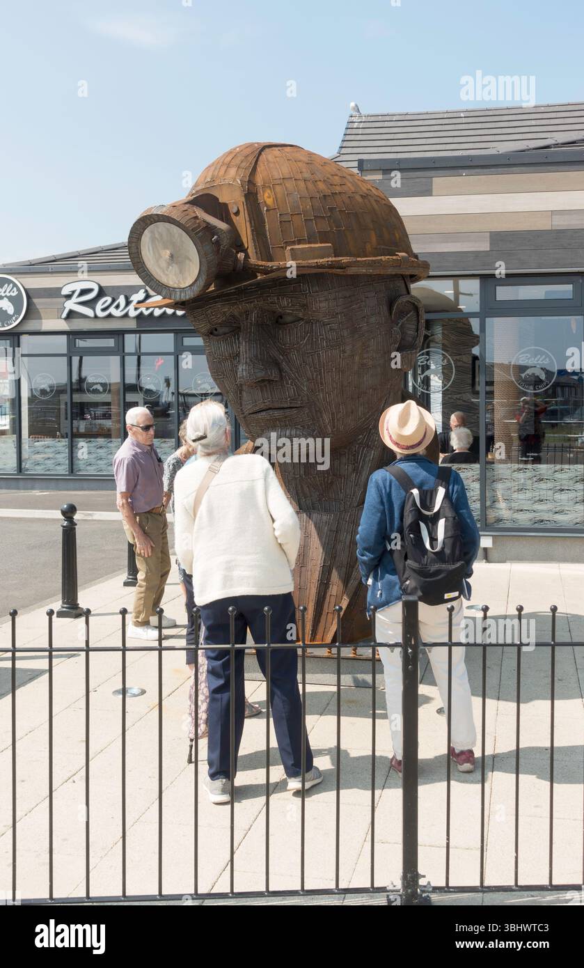 Persone che guardano la scultura di Ray e Sam Lonsdale "Then Gone" o George, raffigurante la testa di un minatore di carbone a Seaham, Co Durham, Inghilterra, Regno Unito Foto Stock