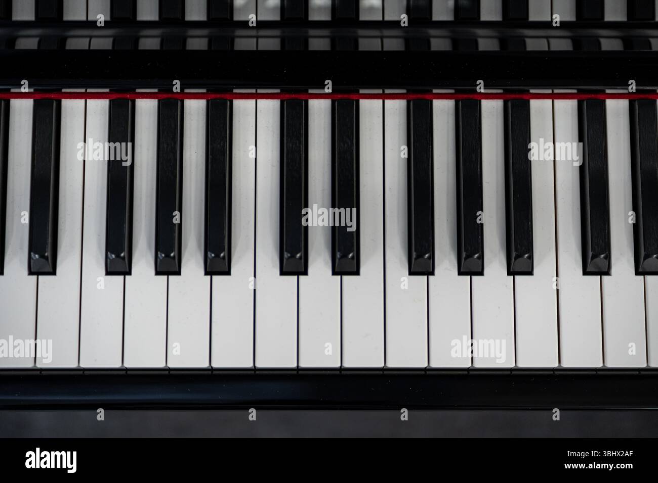 I tasti piano bianchi e neri lucidi creano un contrasto visivo sorprendente, mettendo in risalto la texture e l'eleganza dello strumento Foto Stock