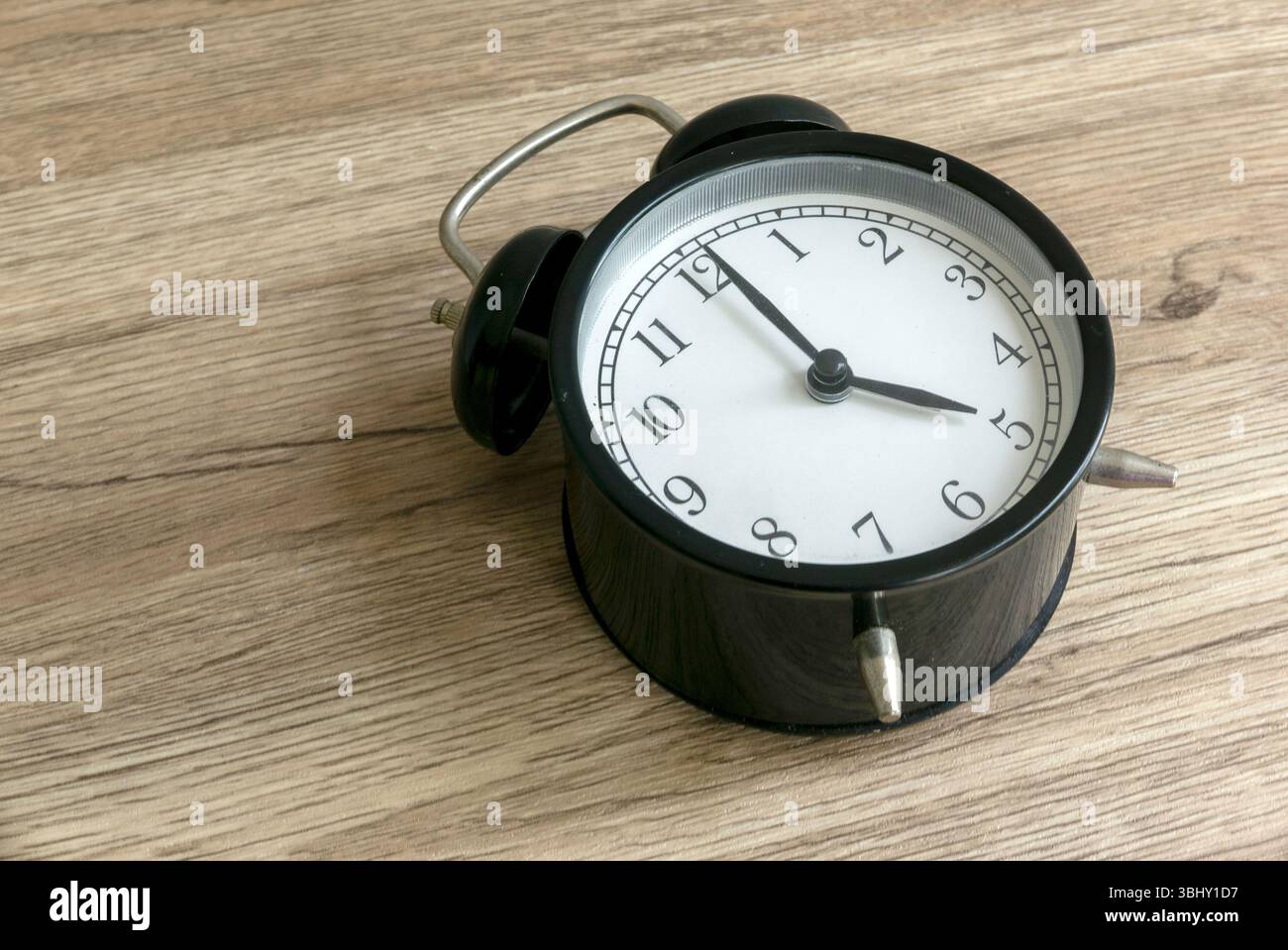 Abbracciare le prime ore del MATTINO: Il significato di una sveglia delle 5 su un tavolo di legno Foto Stock