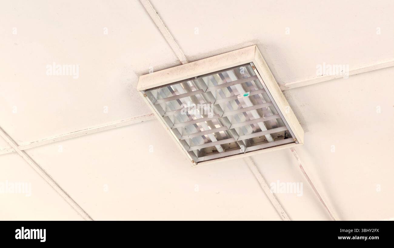 Lampada fluorescente riflettente montata a soffitto in ambiente ufficio Foto Stock