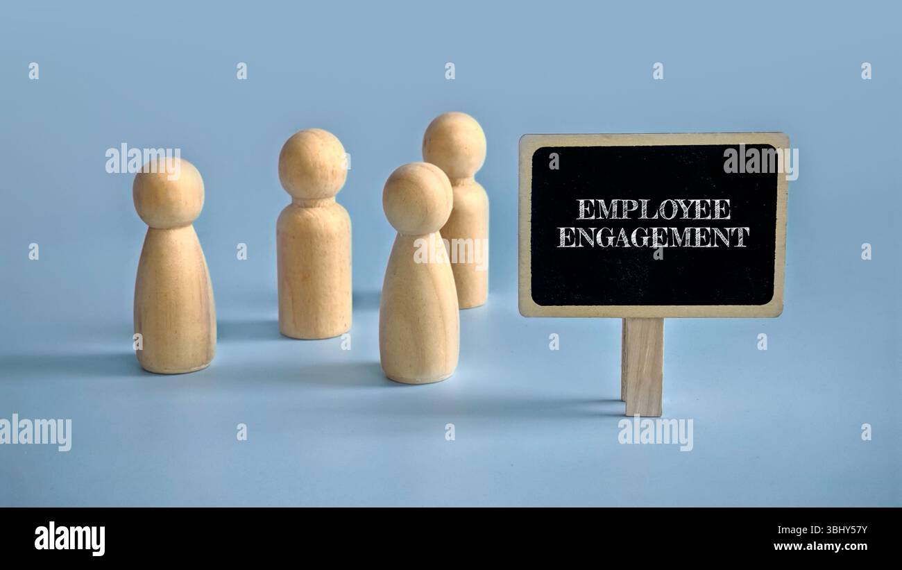 Un gruppo di persone di legno si trova accanto al segno del coinvolgimento dei dipendenti. Foto Stock