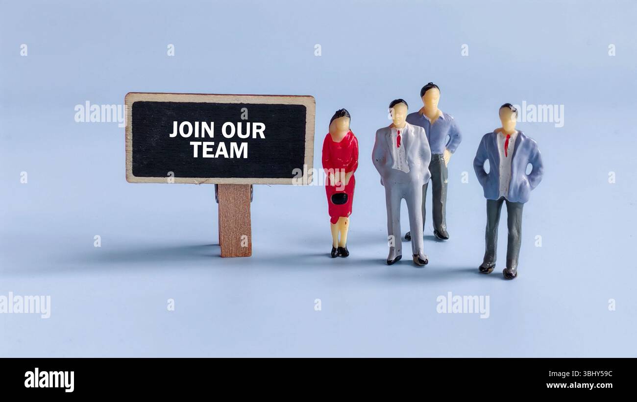 Gruppo di lavoratori professionisti in piedi accanto a un cartello che recita "entra nel nostro team" che rappresenta reclutamento, lavoro di squadra e opportunità di carriera Foto Stock