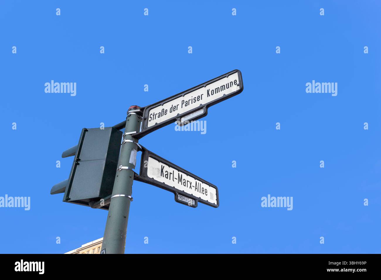 Cartello Karl-Marx strasse e Strasse der pariser Kommune - engl - strada del comune di parigi e Karl Marz Alley nell'ex Berlino Est sotto blu Foto Stock
