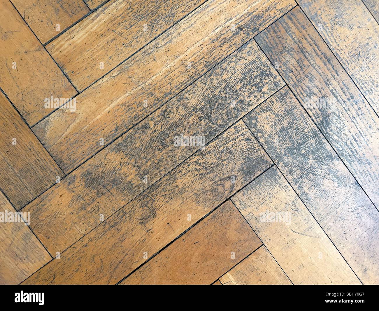 sfondo del vecchio parquet a spina di pesce danneggiato in dettaglio Foto Stock