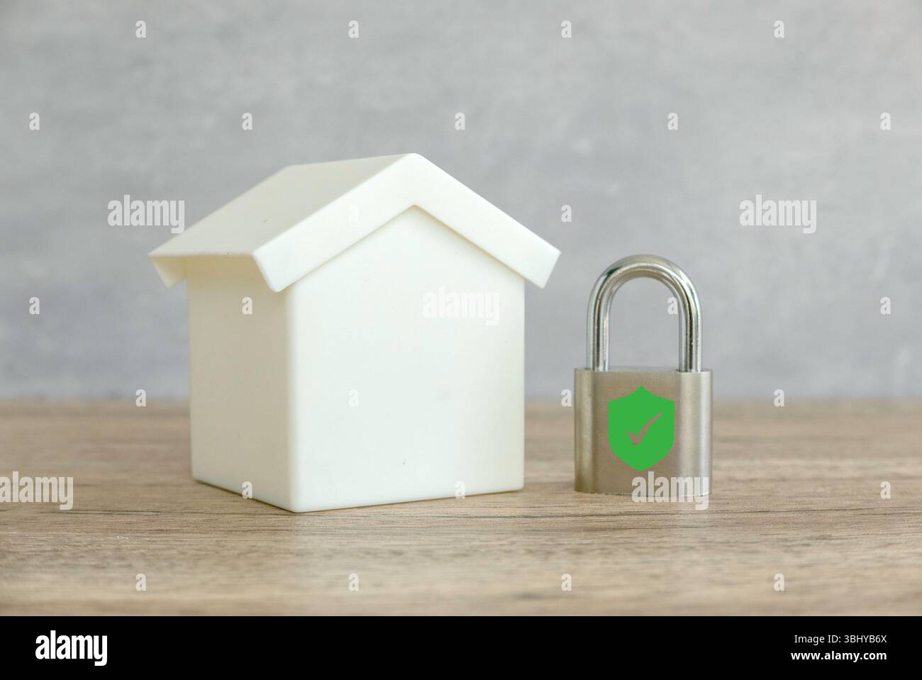 Sicurezza domestica: Un lucchetto con scudo e segno di spunta accanto a una casa dei giocattoli Foto Stock