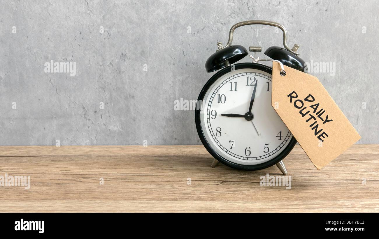 Cravatta per sveglia con cartellino con scritta "Daily routine" su un tavolo in legno con spazio per fotocopie. Foto Stock Cravatta per sveglia con cartellino con scritta "Daily routine" su un tavolo in legno con spazio per fotocopie. Foto Stock