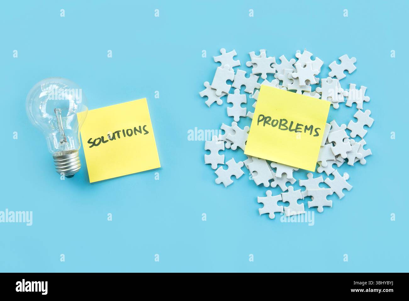 Concetto di soluzioni e problemi con lampadine e puzzle su sfondo blu Foto Stock