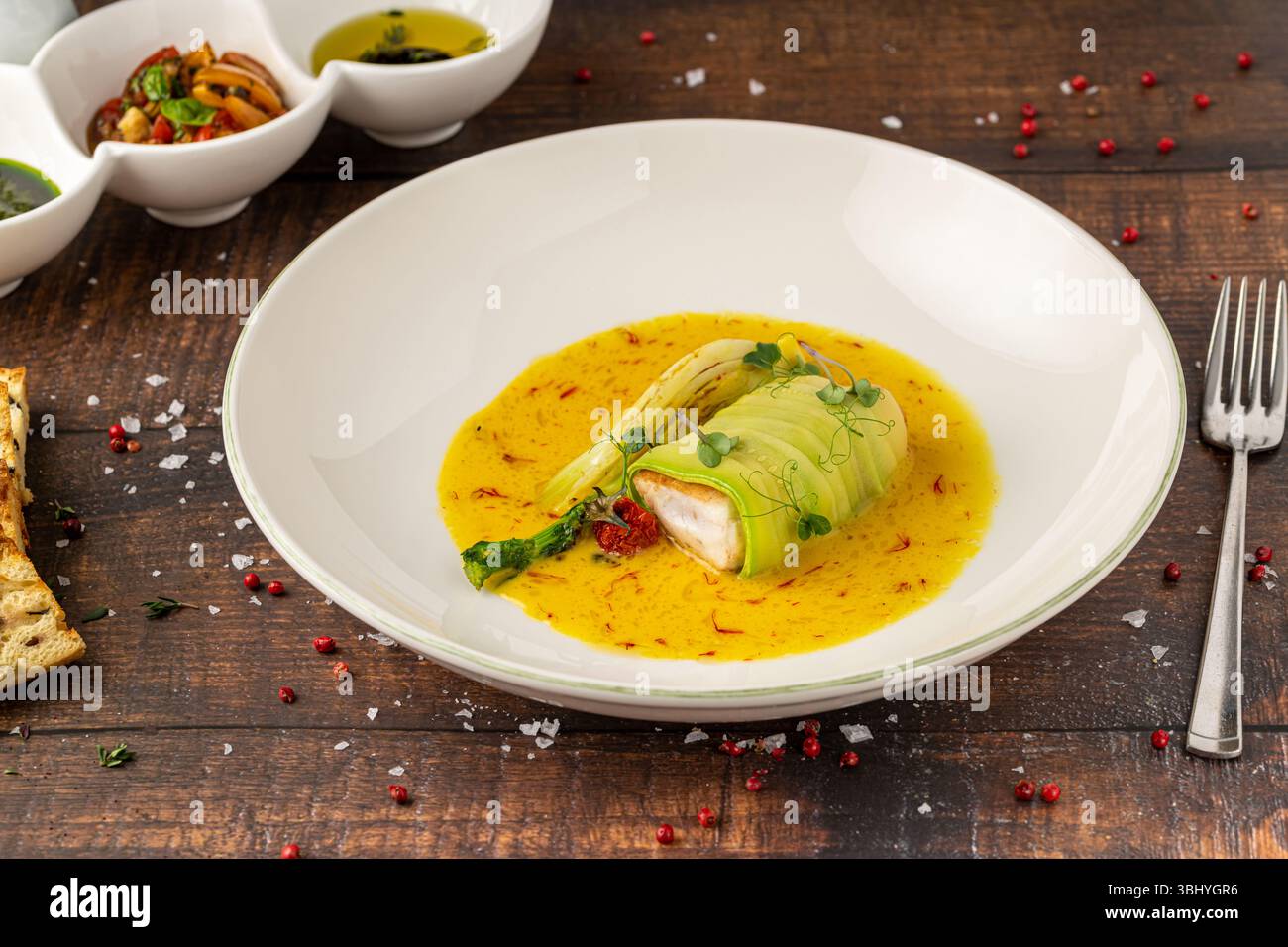 Filetto di pesce ricoperto di zucchine in salsa gialla allo zafferano Foto Stock