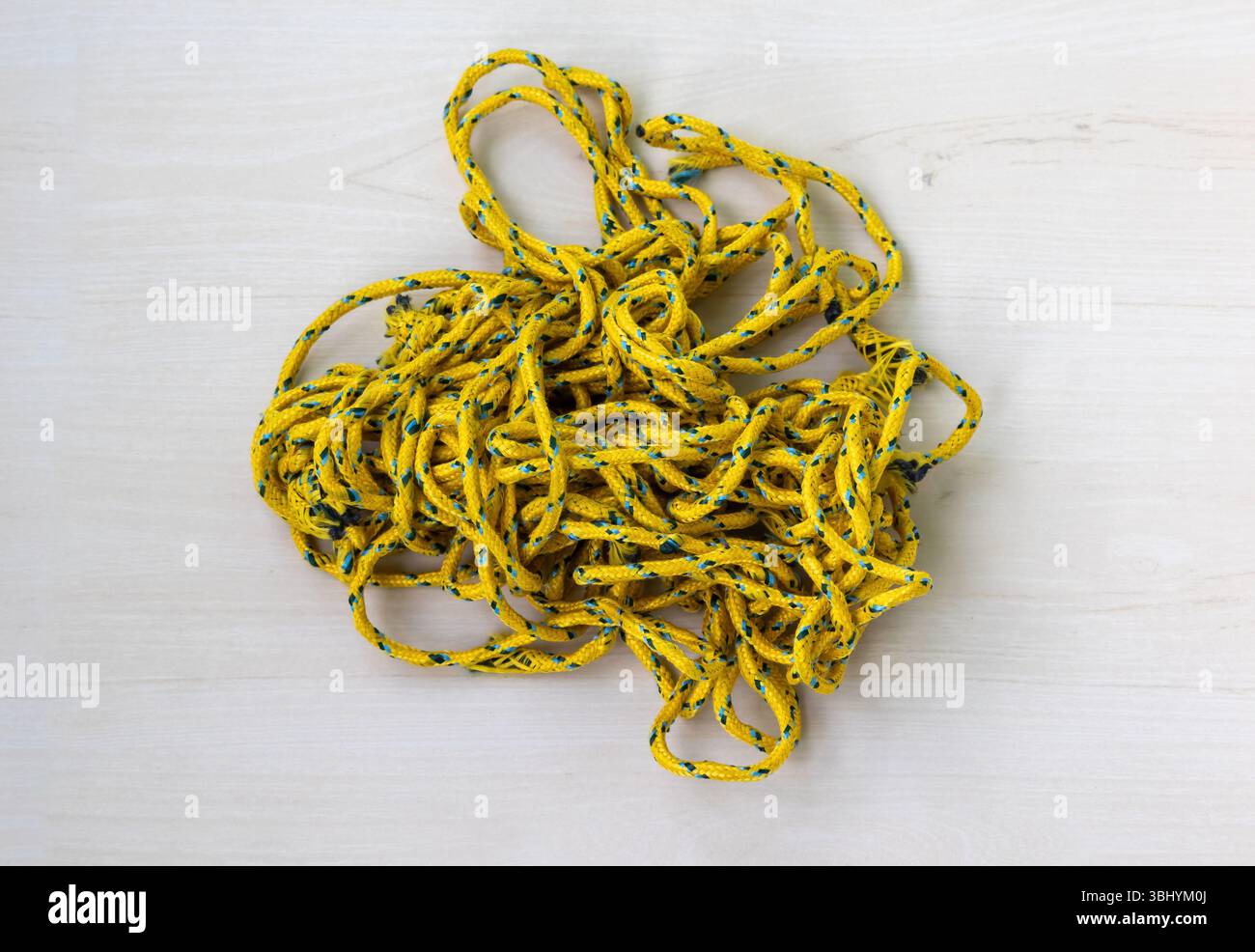 Corda colorata disordinata e resistente avvolto su una superficie in legno. Questa fune intrecciata è adatta per l'asciugatura di stoffe domestiche, il fissaggio di articoli e vari altri componenti Foto Stock